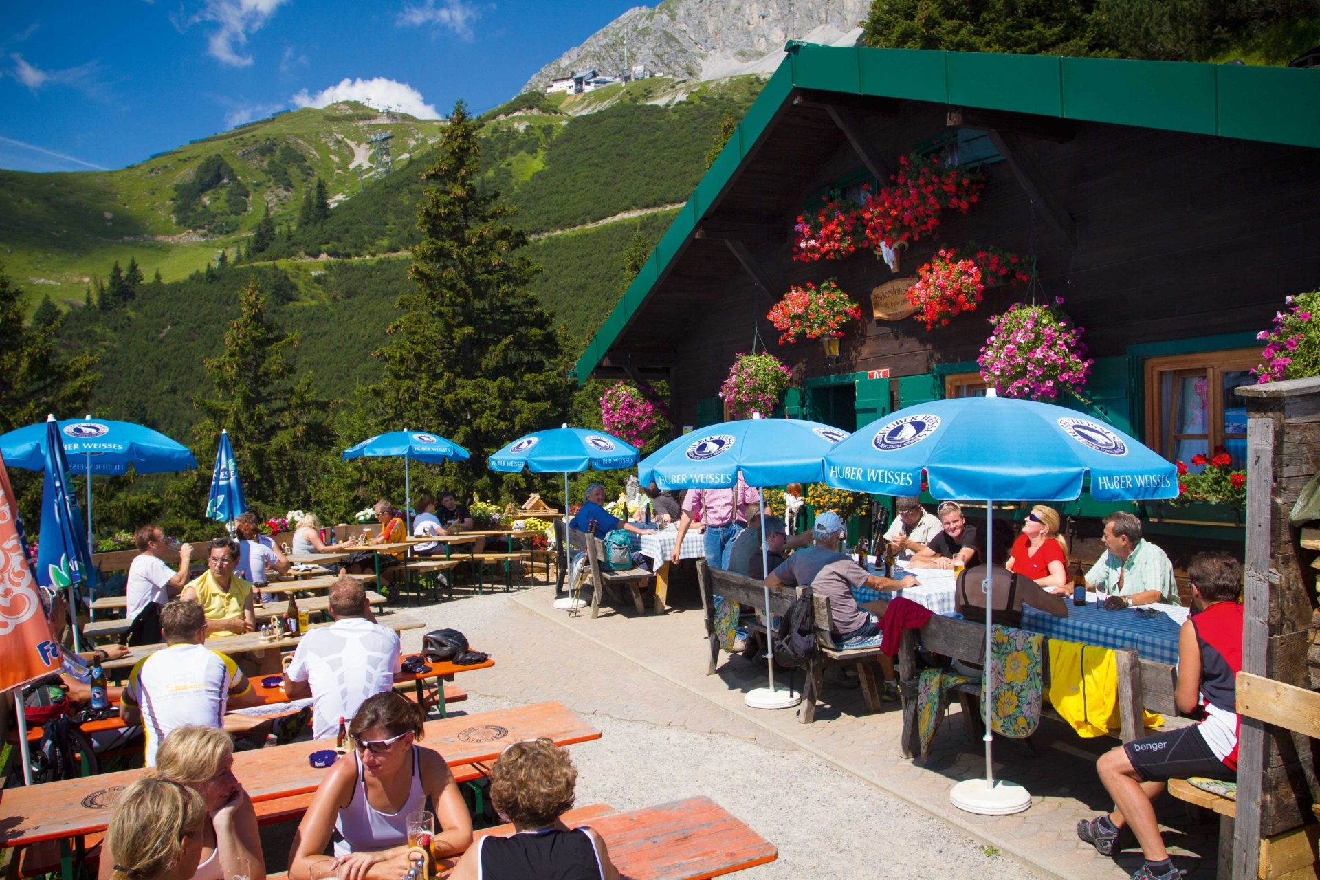 Die Bodensteinalm mit vielen Besuchern bei blauem Himmel.
